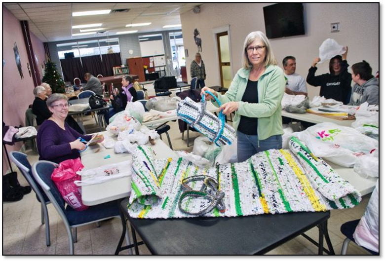 This image depicts a group of volunteers in Kamloops, BC Canada that are weaving and creating sleep mats for those suffering from homelessness - using recycled plastic shopping bags.